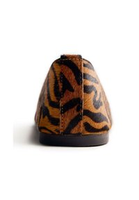 Chaussure plate à rayures tigre brun et noir avec un matériau texturé semblable à de la fourrure. Présente un talon bas et un design à bout rond.