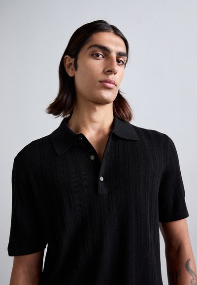 Polo negru cu dungi, cu mâneci scurte și guler moale, având două nasturi la gât și un design ușor fitted.