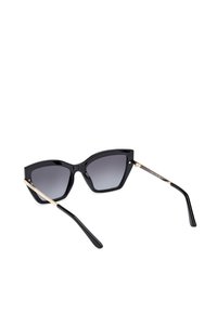 Gafas de sol estilo ojo de gato en negro con lentes degradados oscuros. Cuentan con montura de plástico negro brillante y acentos metálicos dorados en las patillas.