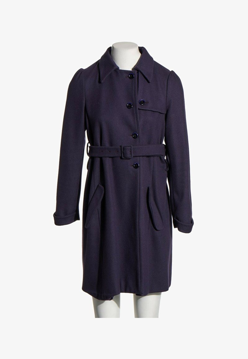 Manteau en laine bleu marine foncé avec boutons, ceinture, col et poches à rabat sur un mannequin blanc sur fond blanc.