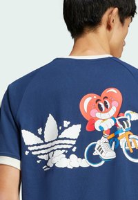 Navy blue short-sleeve t-shirt with a graphic of a cartoon character on a bicycle, featuring white Adidas logo and colorful accents.