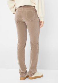 Tan corduroy broek met een slim fit, voorzien van achterzakken en een gladde textuur. Draagt bij lichte schoenen.