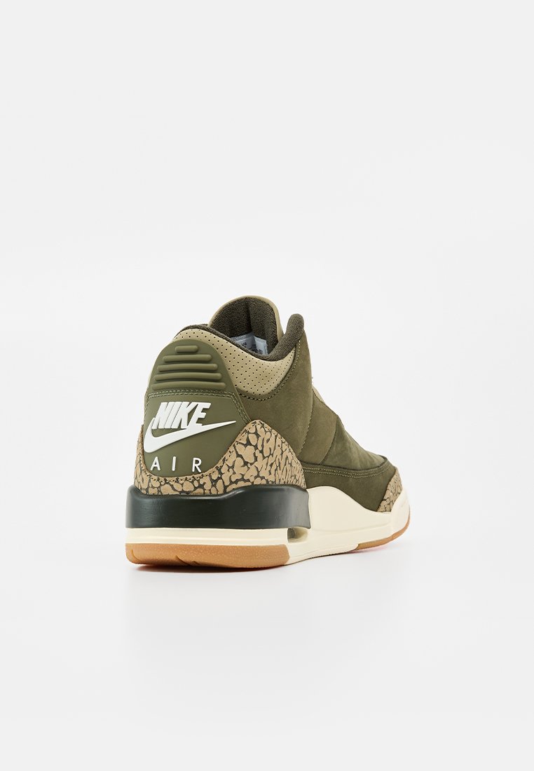 Une basket Nike Air vert olive unique avec des détails beige et noir à motifs, une semelle intermédiaire noire et une semelle extérieure en gomme, vue de l’arrière côté droit.