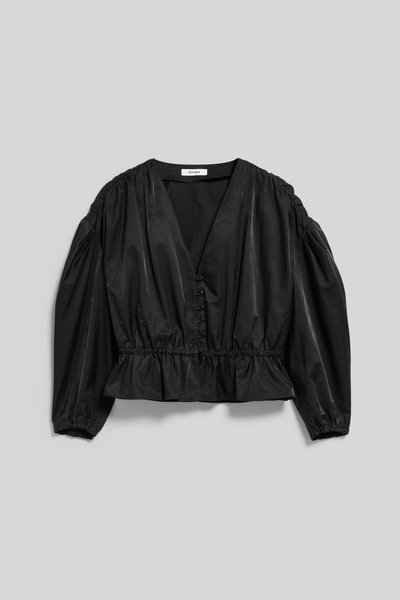 Blouse noire à manches longues avec col en V, boutonnée devant, taille froncée et épaules bouffantes, posée à plat sur fond gris.