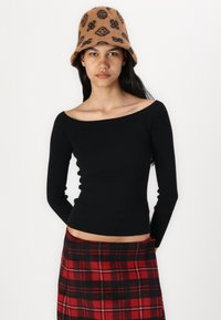 Must mustriba off-shoulder särk mustas toonis, kombineeritud punase ja musta ruudulise seeliku ning pruuni mustriga bucket-hatiga.