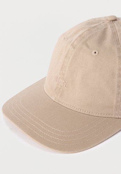 Μπεζ καπέλο μπέιζμπολ με κυρτό γείσο και διακριτικό κεντημένο λογότυπο "WWW," στο μπροστινό πάνελ, σε απλό φωτεινό φόντο.