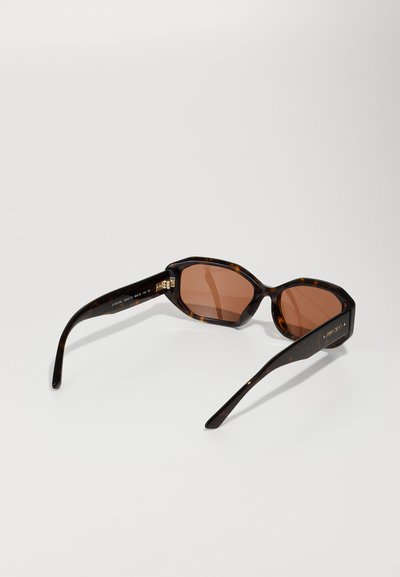 Hexagonal sunglasses with brown tinted lenses. Dark tortoiseshell frames, smooth texture, and slim black temples; gold logo detail on side.