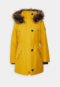 Chaqueta parka amarilla con capucha forrada de piel, dos bolsillos frontales, cintura ajustable con cordón y detalles de botones negros. Textura suave y mangas largas.