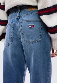 Ανοιχτό μπλε τζιν παντελόνι με ξεθωριασμένη υφή, διαθέτει δύο πίσω τσέπες και ένα μικρό κόκκινο, λευκό και μπλε λογότυπο στη δεξιά τσέπη.