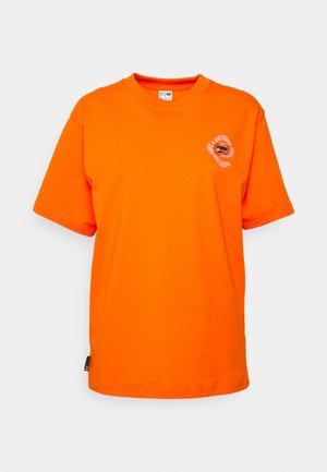 Oranje katoenen t-shirt met korte mouwen, ronde hals en een circulair grafisch ontwerp gedrukt op de linkerborst. Voorzien van een zijlabel.
