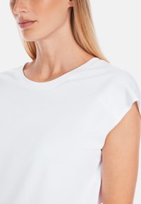 White t-shirt with a round neckline and short raglan sleeves, made from soft fabric with a smooth texture. Simple and clean design.