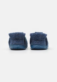 Blue slippers made of textured fabric with a soft finish, featuring a rubber sole and a folded cuff design at the heel.