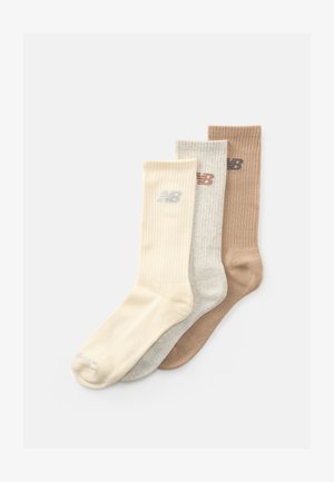 Tre par ribbade ankelsockor i krämfärgad, ljusgrå och ljusbrun med en liten logotyp nära toppen.