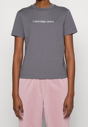 Grå bomulds t-shirt med korte ærmer og rund hals. Har "Calvin Klein Jeans" logo i hvidt på tværs af brystet.