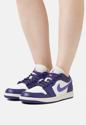 Matalat lenkkitossut, joissa valkoinen nahkapäällinen violeteilla yksityiskohdilla, sileä pinta, rei'itetty kärki ja violetit nauhat.