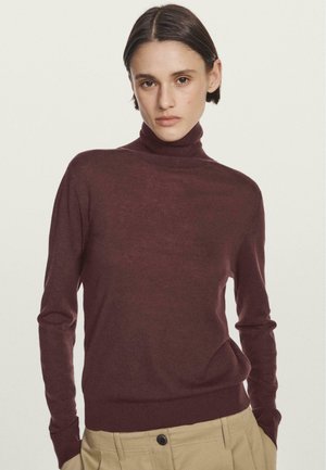 Maglione a dolcevita bordeaux realizzato in tessuto morbido e leggero, con maniche lunghe e vita aderente, abbinato a pantaloni khaki.