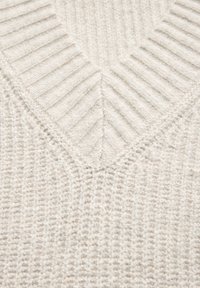 Maglione lavorato a maglia color crema caratterizzato da una trama a coste, scollatura a V e un delicato motivo diagonale sul petto.
