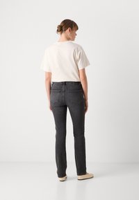 Witte katoenen t-shirt met korte mouwen, in combinatie met donkergrijze skinny jeans. De outfit heeft een eenvoudig design en standaard zakken.