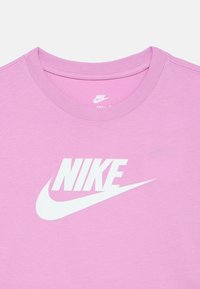 Roosa puuvillane t-särk ümmarguse kaelusega, millel on suurelt valge Nike'i logo rinnal ja sile tekstuur.