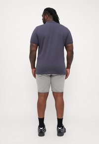 Marineblå polo skjorte med korte ermer, kombinert med lys grå denimshorts. Outfiten har pustende stoff og en avslappet passform.