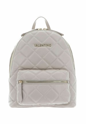 Mochila gris acolchada con herrajes dorados, que incluye un asa en la parte superior y un bolsillo con cremallera en la parte delantera, textura suave y detalles del logo.