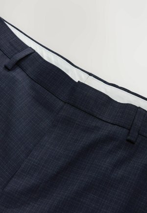 Navyblaue Hose mit dezentem Karomuster, aus strukturiertem Stoff. Verfügt über einen weißen Innenbund und Gürtelschlaufen.