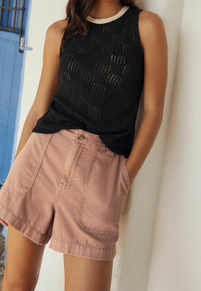 Débardeur noir en maille avec un motif texturé en vagues et un col blanc tressé, associé à un short en denim rose avec des poches latérales.