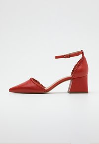 Chaussure à talon en cuir rouge avec un bout pointu, une bride de cheville et des détails tissés le long du bord. Design à talon carré.