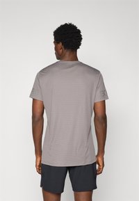 Grå kortærmet sports T-shirt med tekstureret overflade, med rund halsudskæring og subtilt logo på venstre ærme.