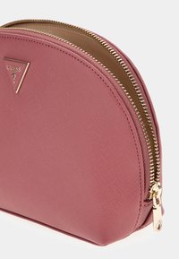 Pochette rosa testurizzata con una parte superiore curva, cerniera e accessori dorati. Presenta una piastra logo triangolare sul davanti per un tocco di dettaglio.