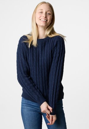 Dunkelblauer gestrickter Pullover mit einem strukturierten Kabelmuster, Rundhalsausschnitt und gerippten Bündchen. Kombiniert mit blauen Jeans.