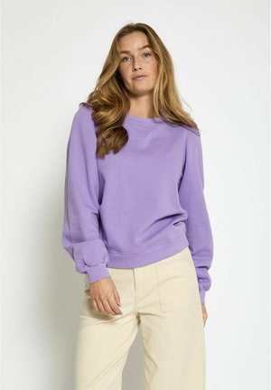 Lilla sweatshirt ümara kaelusega ja puhvsete pikkade varrukatega; valmistatud pehmest materjalist; kombineeritud beežide laia säärega pükstega.