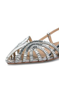 Pantofii plata din metalic argintiu cu un design deschis, având curele curbate, vârful ascuțit și o branț neted de nuanță bej. Apariție clasică și elegantă.