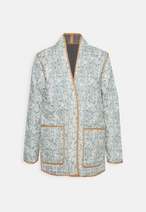 Gewatteerde jas met bloemmotief en strepen, beige bies, voorzakken en een sjaalkraag, getoond tegen een eenvoudige achtergrond.