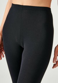 Zwarte leggings gemaakt van een soepele, rekbare stof. Bevatten een hoge tailleband en een aansluitend ontwerp, wat zorgt voor een nauwsluitende pasvorm.