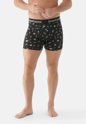 Black boxer briefs with a waistband labeled “Smartwool” featuring a repeating pattern of various tools and items in colors such as red, blue, and white.
