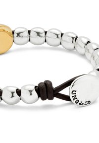 Pulsera con un charm en forma de corazón de oro, cuentas redondas de plata y acentos de cordón de cuero oscuro; presenta un acabado brillante y detalle del logotipo.