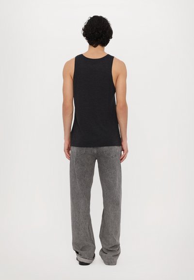 Un haut sans manches noir et un jean gris décontracté. Le tissu semble doux avec une texture subtile ; le haut a un col rond et une coupe ample.