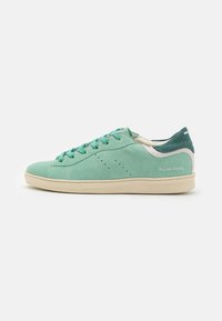 Sneaker verde in suede con superficie texture, dotate di punta rotonda, lacci piatti e suola beige a contrasto. Logo sul lato.