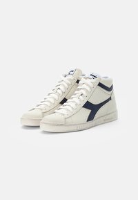 Des baskets montantes en cuir crème avec des accents marine, dotées d'un dessus texturé, d'un bout rond, de lacets plats et d'une semelle en caoutchouc.