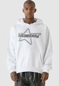 Hoodie bianco con una grande grafica grigia "Starboy" all'interno di un contorno a stella, tasca a marsupio e polsini a costine sulle maniche e in vita.
