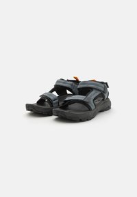 Sandales de sport avec des brides grises réglables, semelle noire, semelle intérieure texturée et accent orange. Conçues pour le confort et une utilisation en plein air.