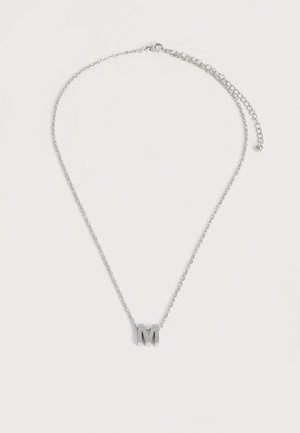 Collier chaîne en argent avec un pendentif en forme de lettre M en argent et un fermoir réglable sur fond blanc.