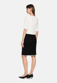 White short-sleeve top paired with a black textured skirt featuring a decorative hem, and black pointed-toe heels with a low heel.