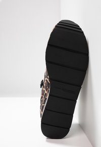 Buty wsuwane w leopardzie z teksturowaną czarną gumową podeszwą, z akcentem w postaci bocznej klamry i miękką tkaniną na cholewce.