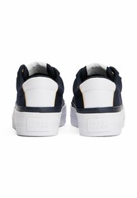 Sneakers in tela navy con accenti in pelle bianca, suola in gomma testurizzata e dettaglio del logo sul retro. Design a punta rotonda e alla caviglia bassa.