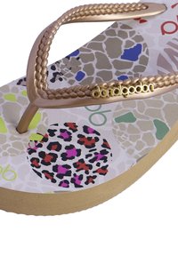 Chancla de bronce con tira trenzada y acento dorado. La suela impresa presenta patrones de animales en varios colores sobre un fondo claro.