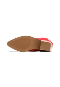 Zapato rojo con un empeine texturizado, material de cuero y un tacón bajo de goma color marrón. La suela presenta estrías horizontales para mayor agarre.
