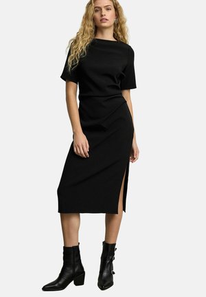 Robe midi noire à manches courtes et fente sur le côté. Fabriquée en tissu lisse, avec une taille cintrée et une silhouette droite.