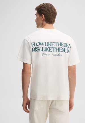 Mann trägt weißes T-Shirt mit türkisfarbenem Text "Flow like the sea rise like the sun" und kleinerem kursivem Text darunter auf dem Rücken.